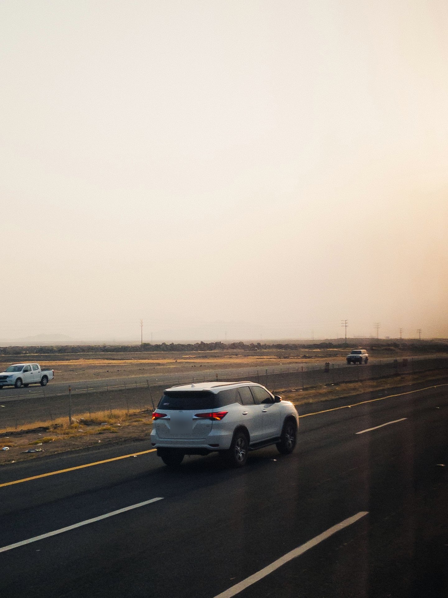 White SUV driving down an empty highway at sunrise — an example of the SUV category