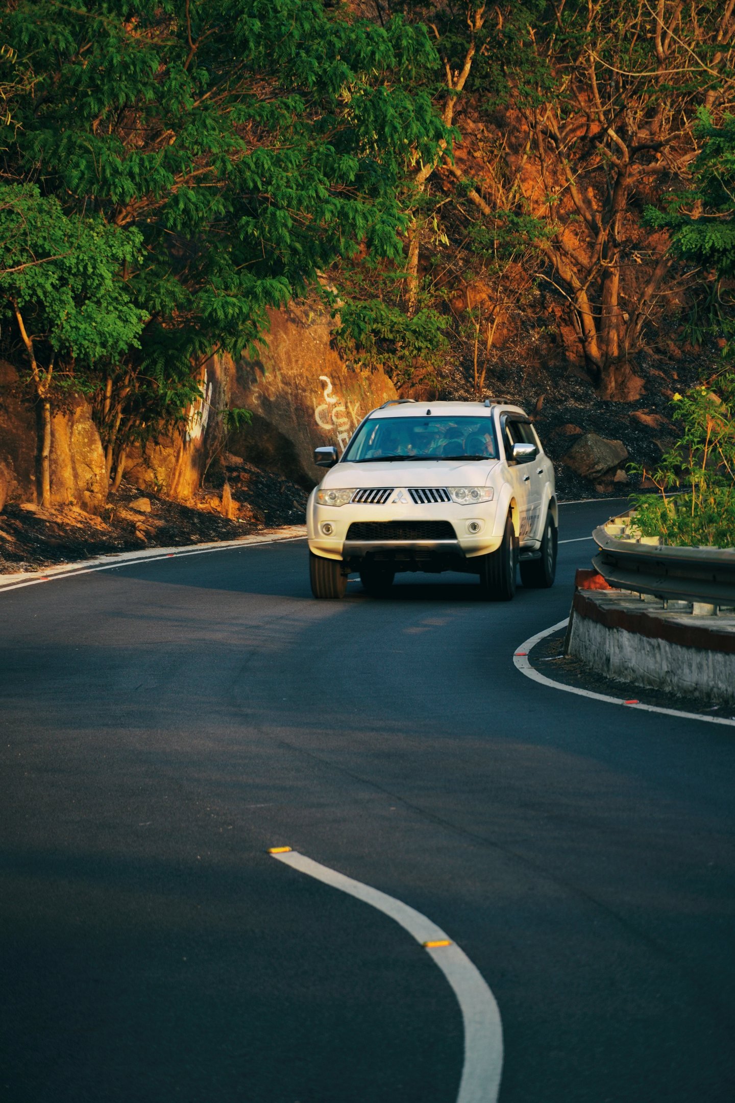 White SUV driving up a winding road through wooded hills